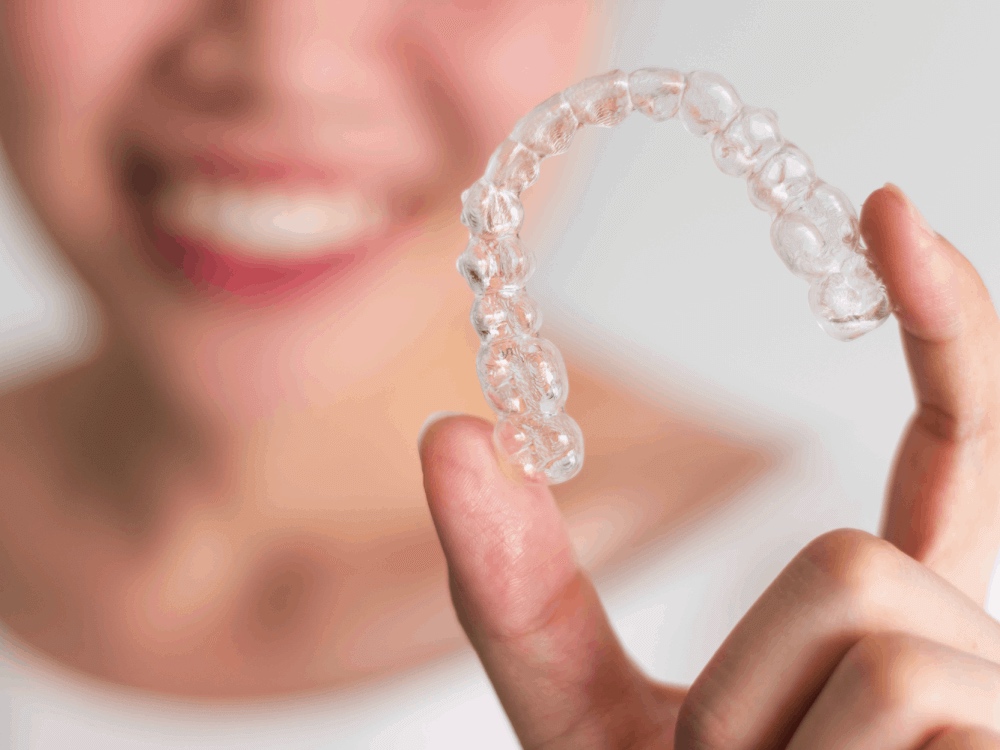 Smiling woman holding a clear plastic retainer in her hand