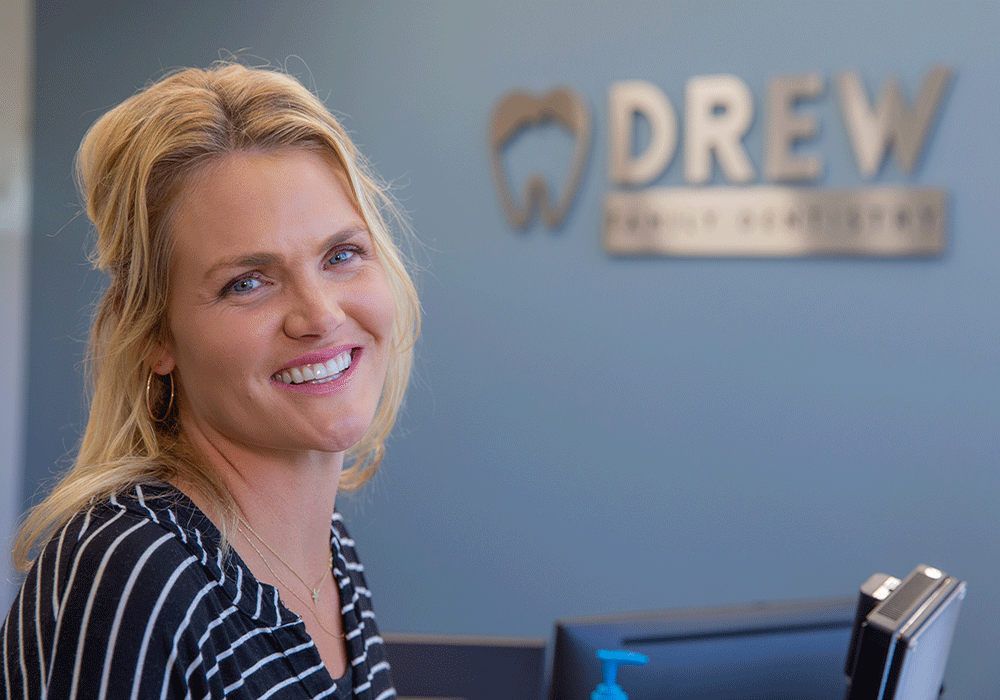 Woman smiling in front of Drew Family Dentistry sign
