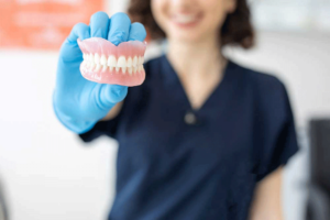 A dentist holding a set of dentures in her hand