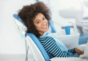 Woman with dark hair smiling and sitting in a dental chair