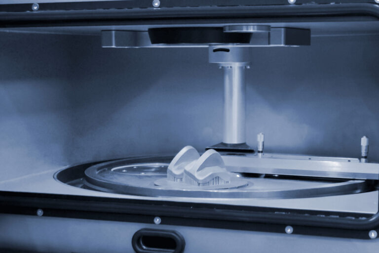 Close-up view of a 3D printer in operation, showcasing the creation of a complex object on a circular build platform with a vertical support structure above it.